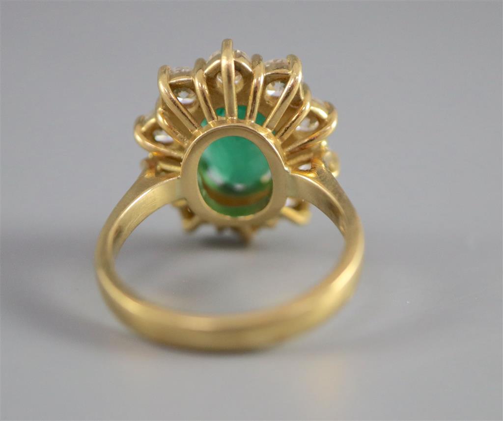 A modern 18ct gold, emerald and diamond oval cluster ring,